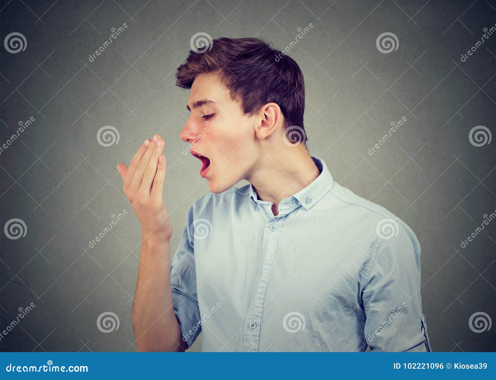 man checking his breath with hand.