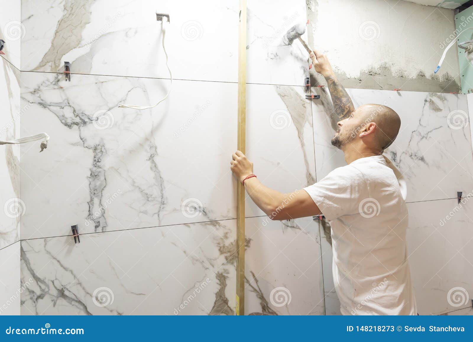 man checking proper ceramic tile installation with level on wall, closeup. building and renovation works