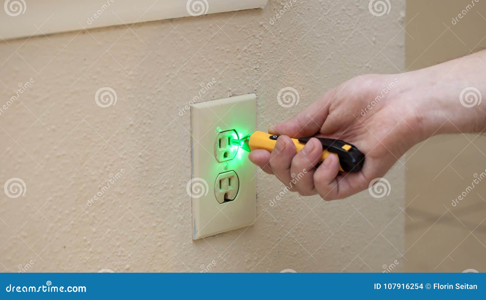 Man Checks If There is Power in Wall Socket with Tool Stock Photo