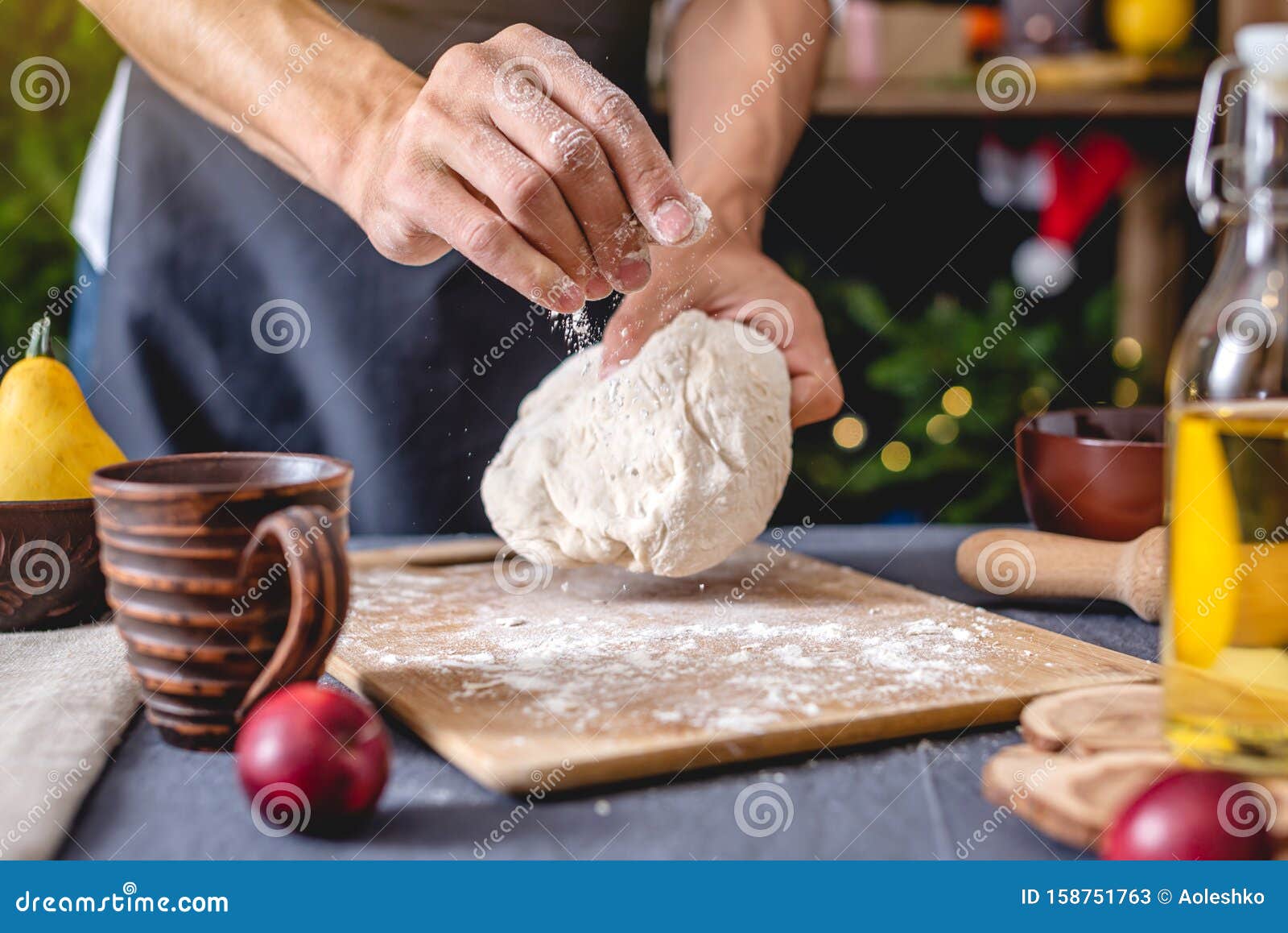 man chef in a black apron kneads the dough with hands for christmas baking. joyful cooking for festive new year table