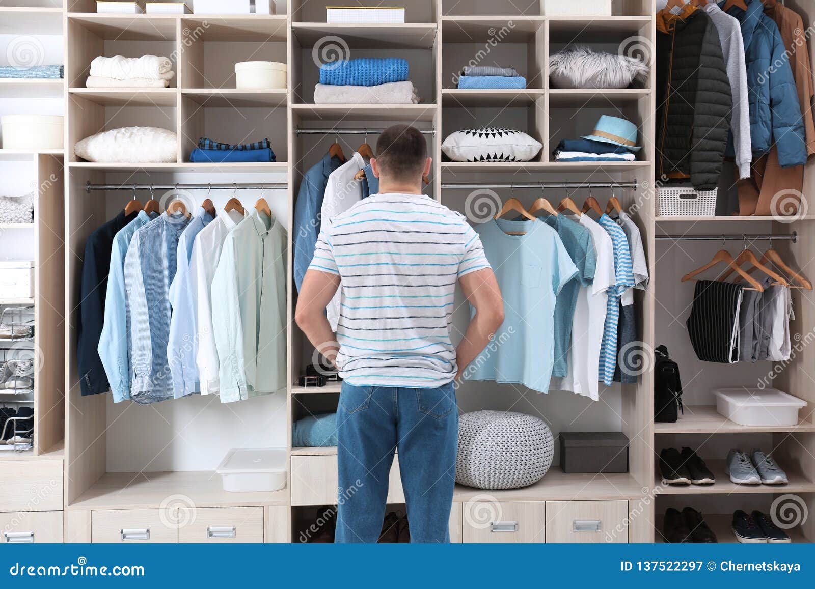 man choosing outfit from large wardrobe closet with clothes, shoes and home stuff