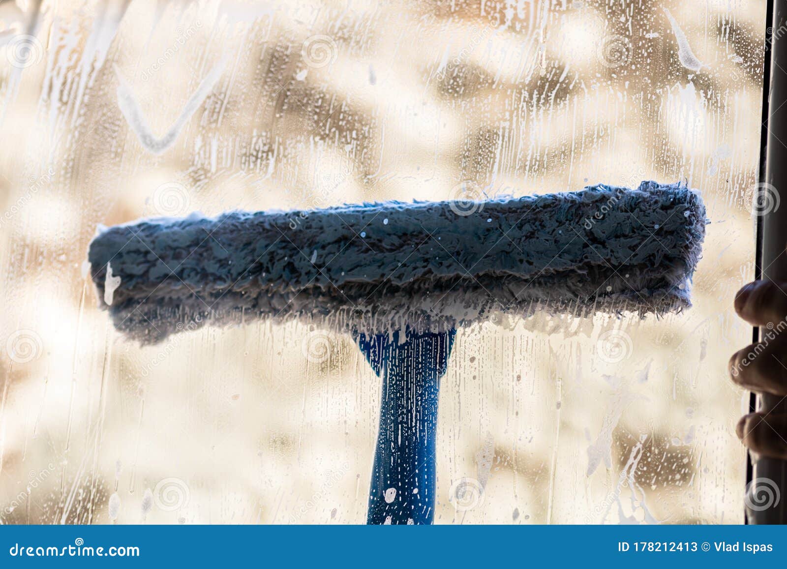 Man Cleaning Window Using Window Cleaning Squeegee and Cleaning Sprayer
