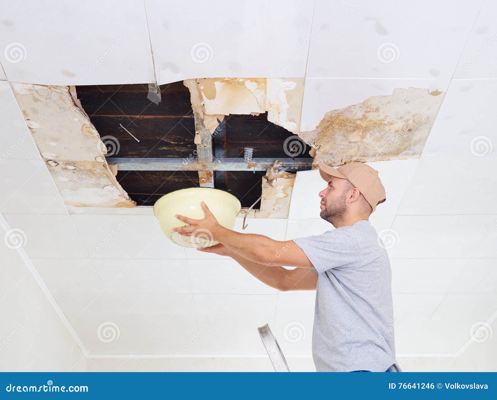Man Collecting Water In Basin From Ceiling Ceiling Panels Damag