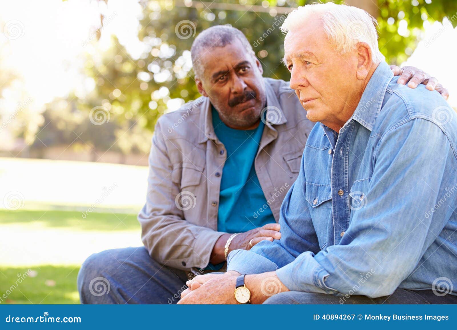 man comforting unhappy senior friend outdoors
