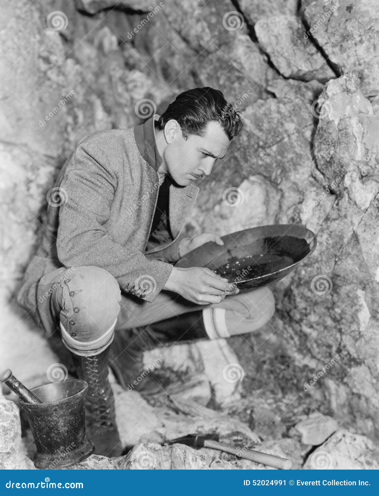 man crouching and panning for gold