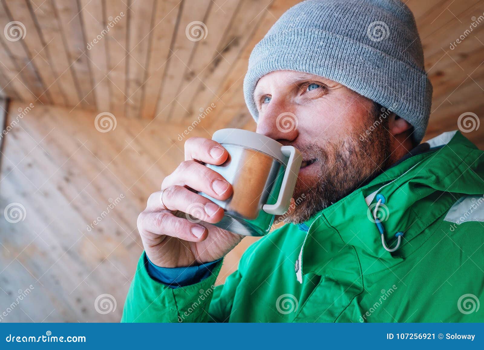 man with cup of hot drink warms on open winter air