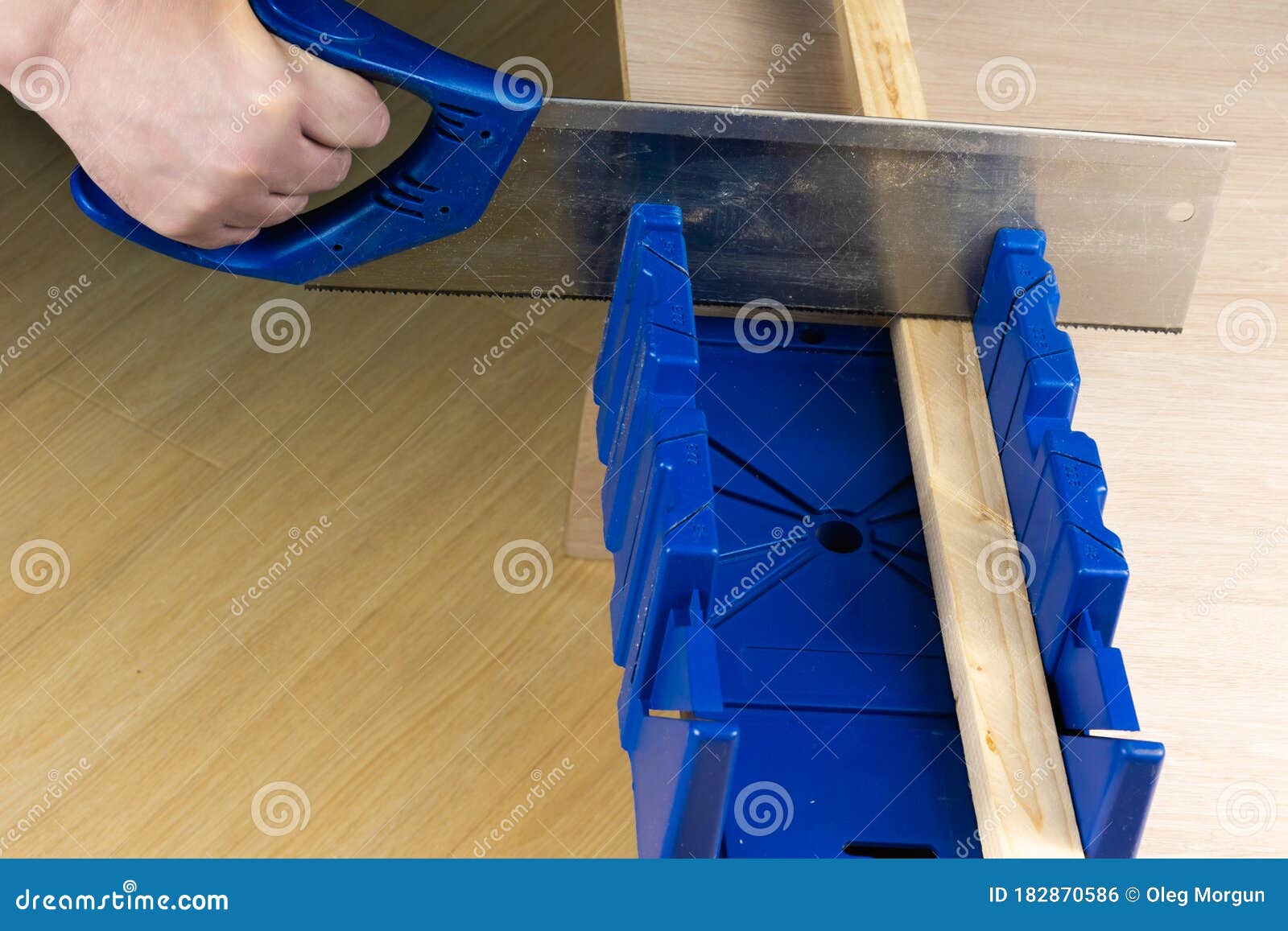 Man Cutting a Slat of Wood Using a Saw and Miter Box Stock Photo