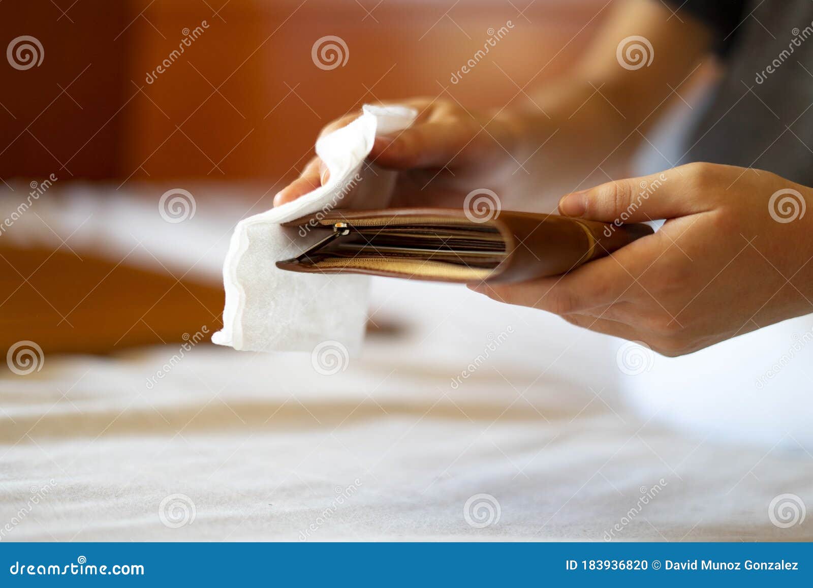 man disinfecting his wallet with a disinfecting wipe.