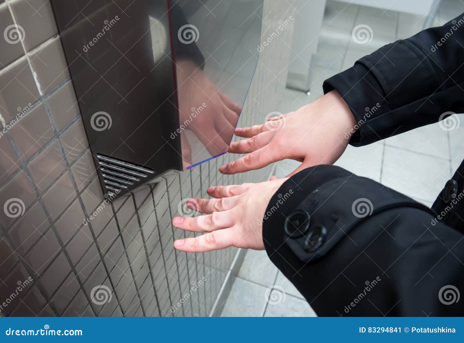 man dries wet hands with an electric hand dryers