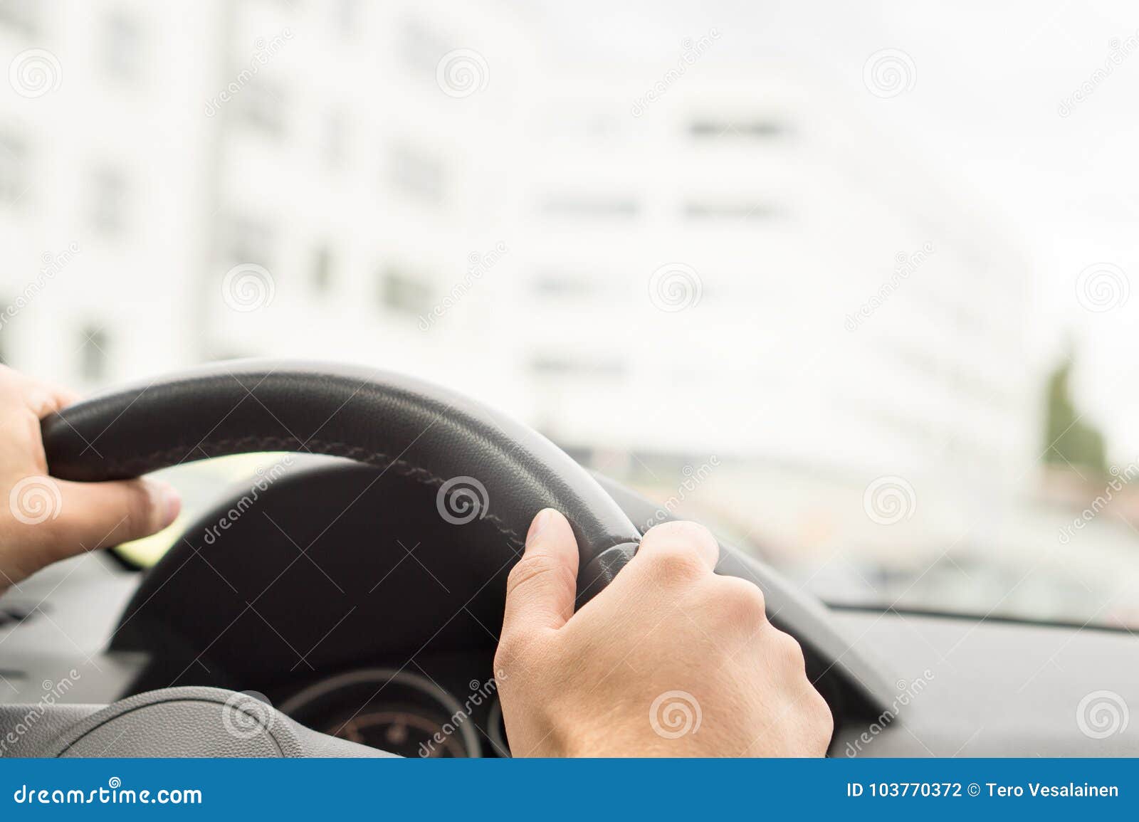 man driving car in city. driver holding steering wheel.