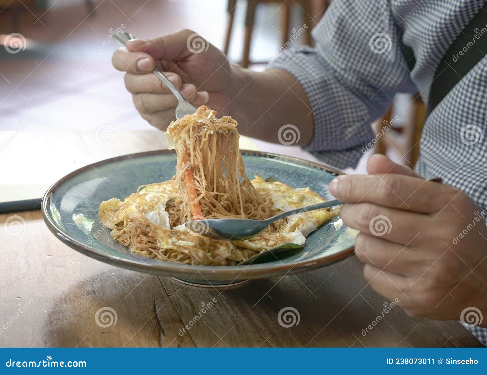 man eating stir fry noodles wrapped with egg omellete