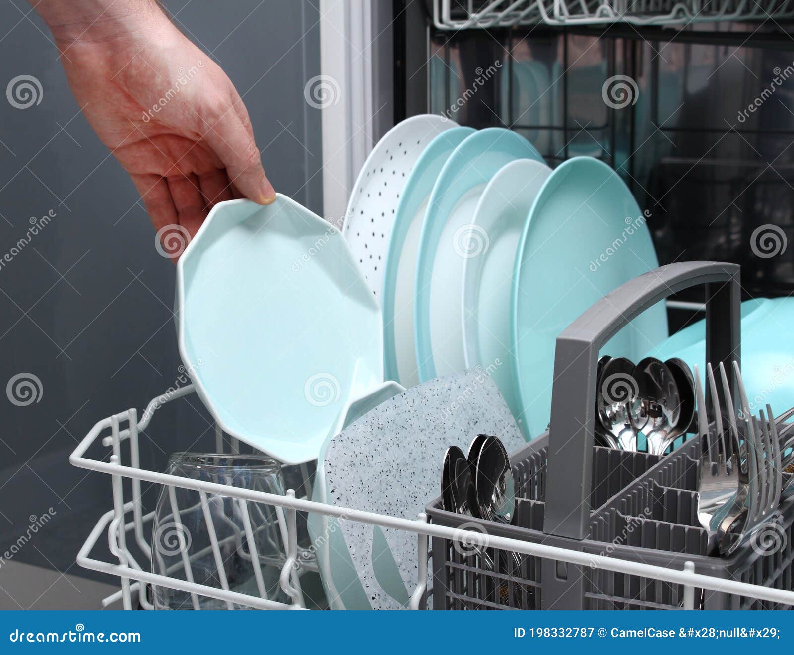 Man Empty Out the Dishwasher in Kitchen.Closeup of Male Hands Loading