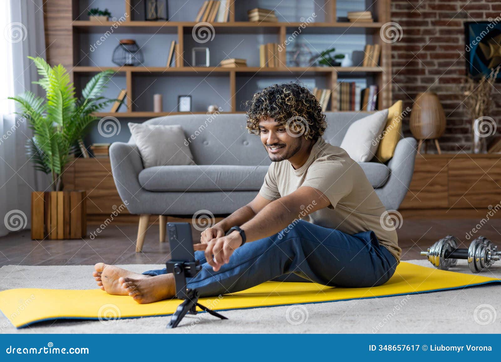 man engaging in home workout while filming with smartphone on exercise mat