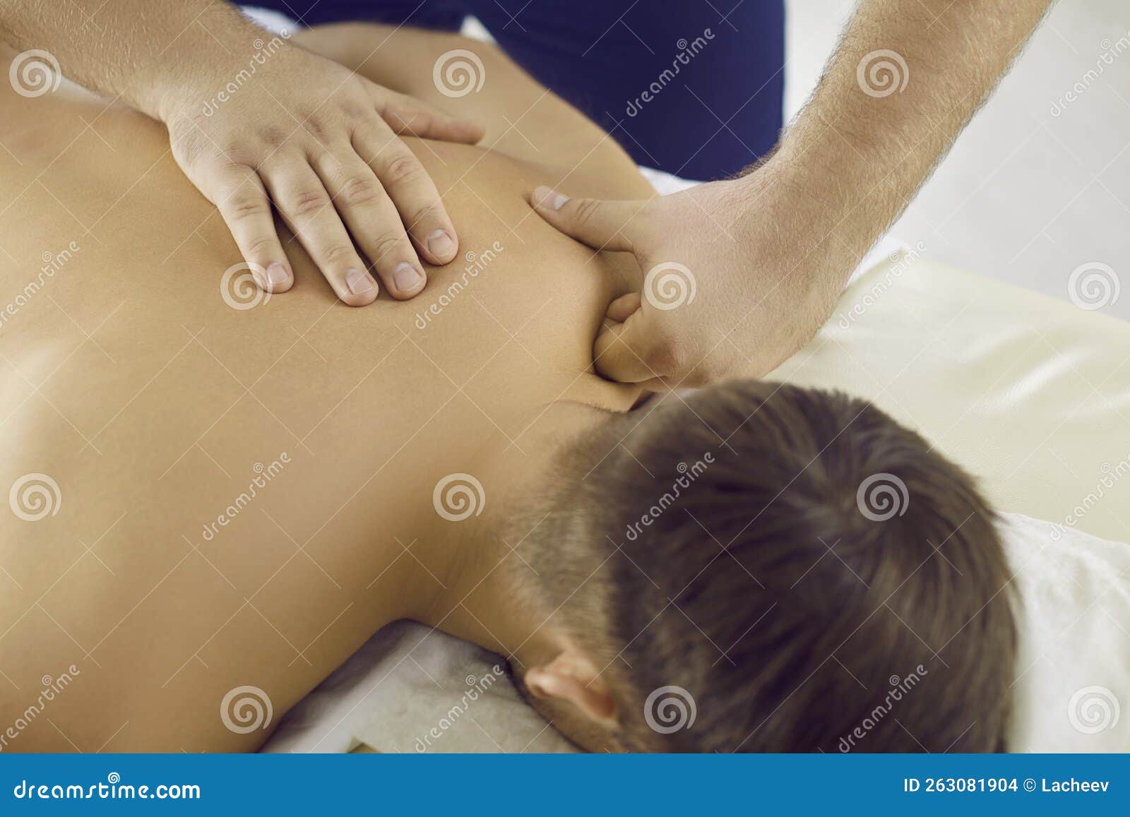 man enjoying relaxing, remedial back massage done by professional masseur at massage room