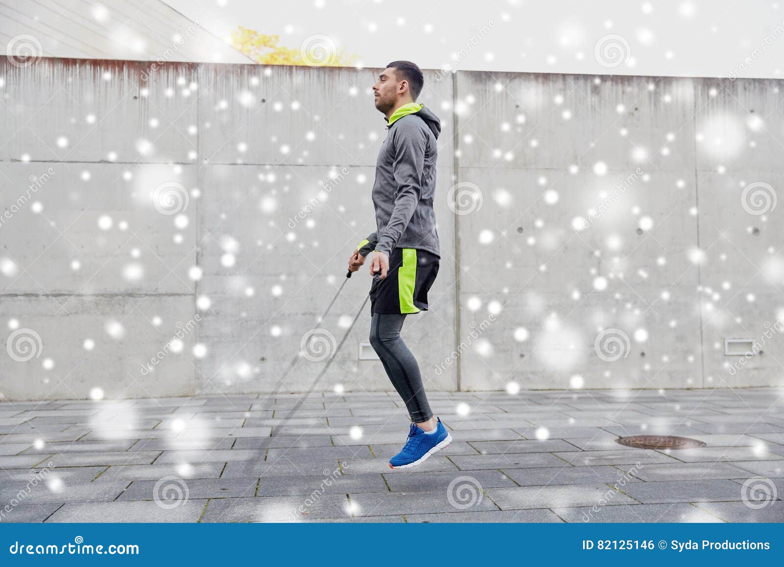 Man exercising with jump-rope outdoors. Fitness, sport, people, exercising and lifestyle concept - man skipping with jump rope outdoors over snow