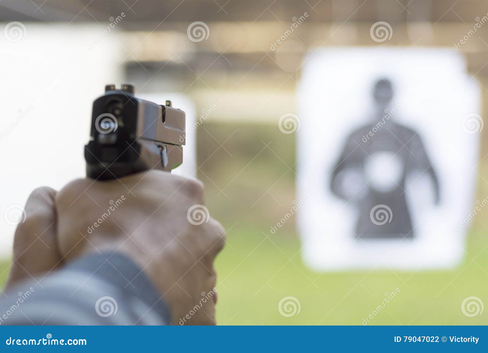 man firing pistol at target in shooting range
