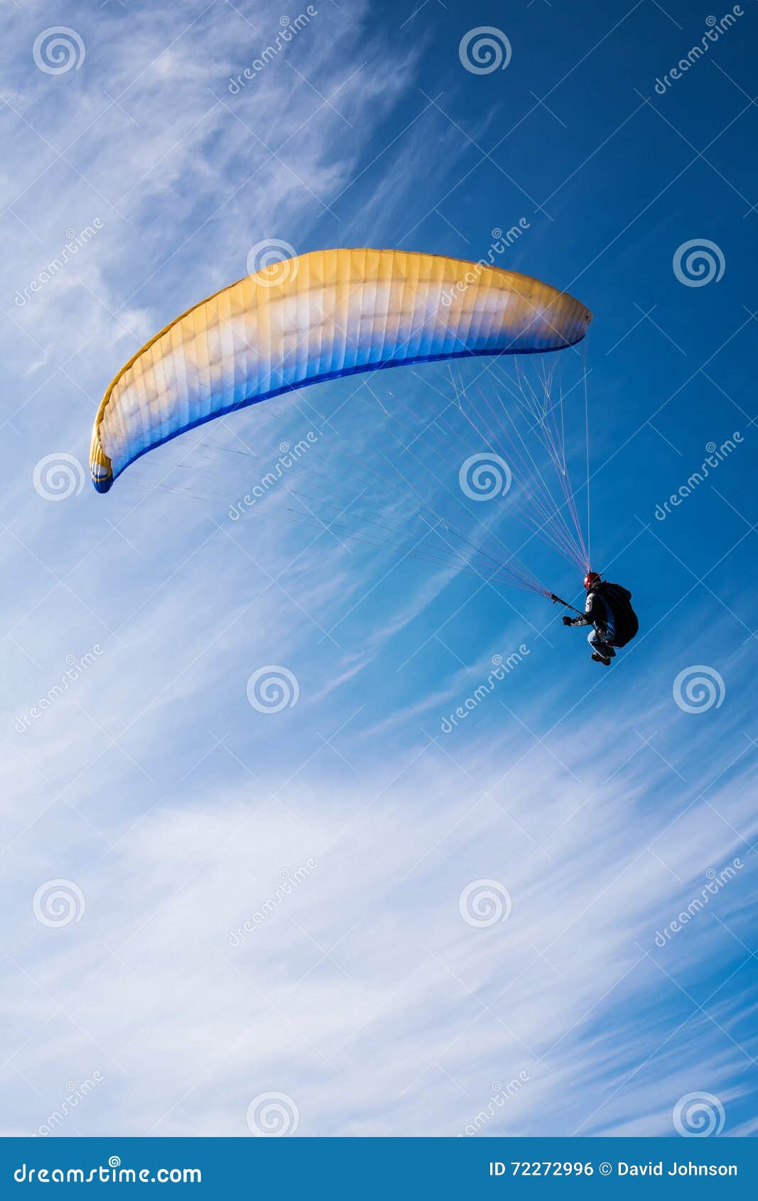 man flying yellow and blue parasail