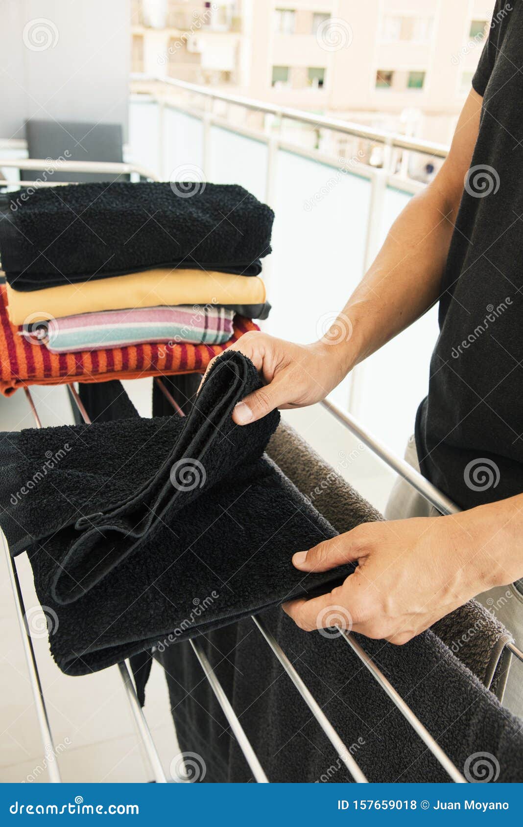 Man Folding Clothes On A Drying Rack Stock Photo - Image 