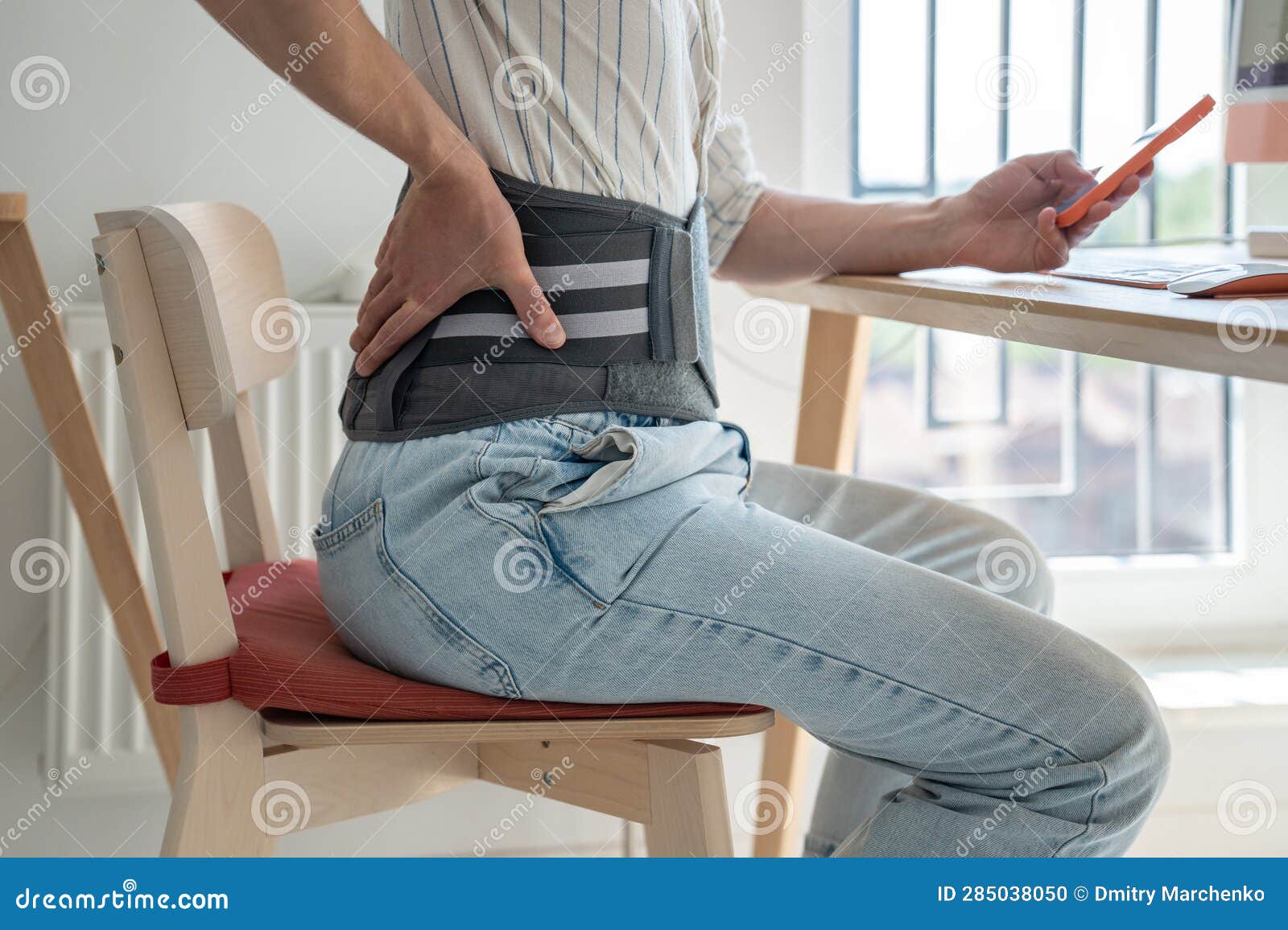 man freelancer wearing back support belt working remotely from home