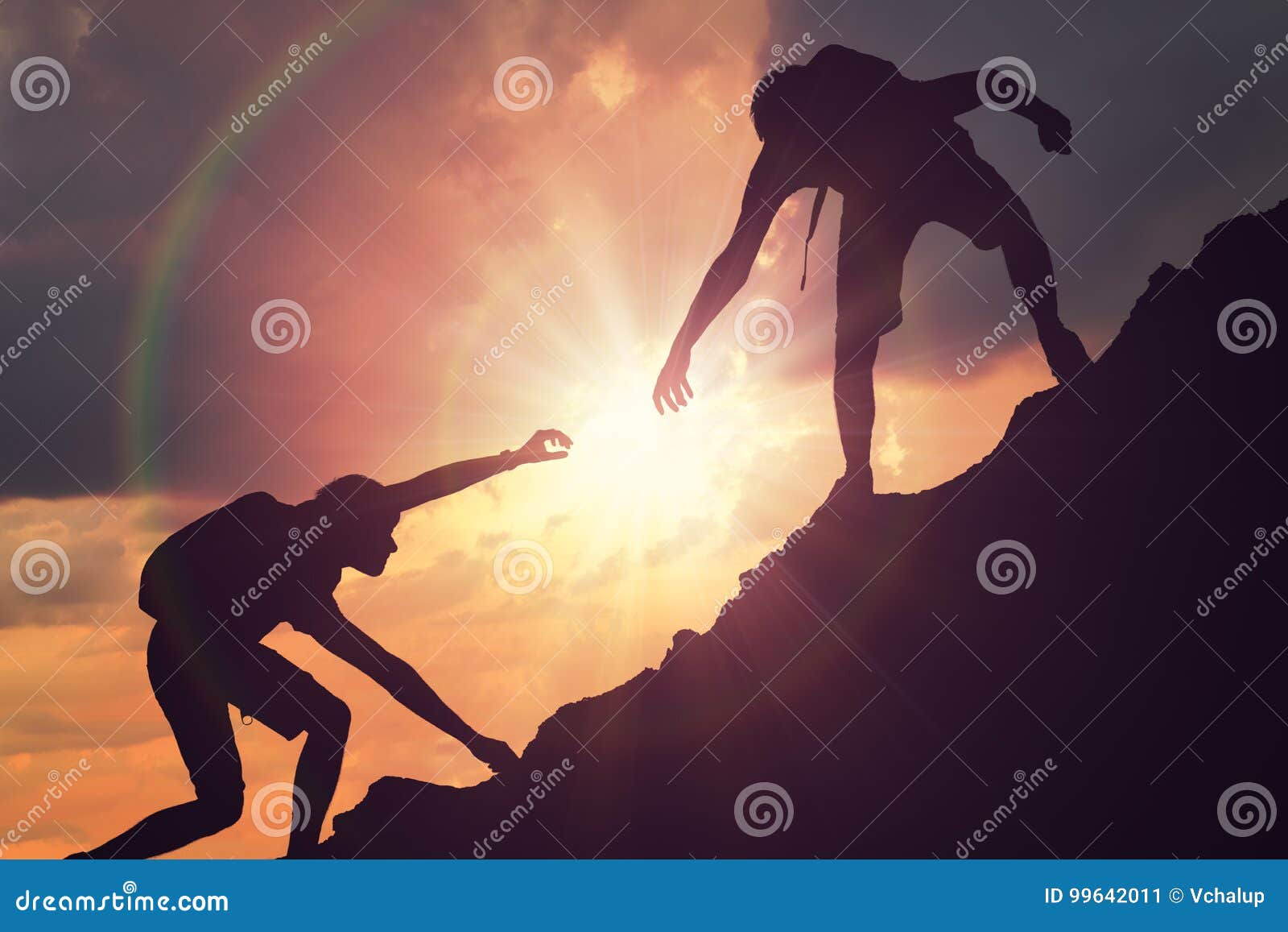 man is giving helping hand. silhouettes of people climbing on mountain at sunset