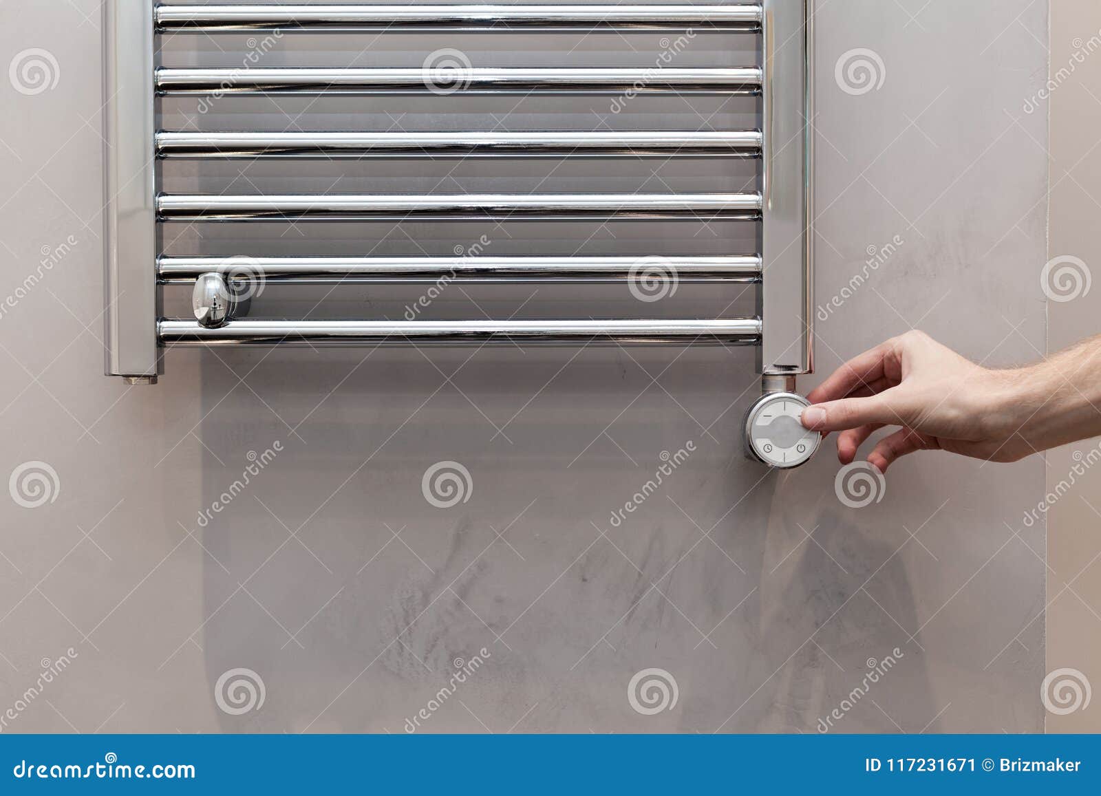 the man hand regulates the temperature in the heated towel rail in bathroom.