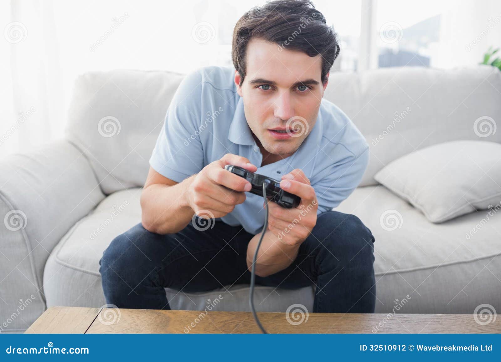 Man Having Fun with Video Games while he is Sat on a Sofa Stock Photo