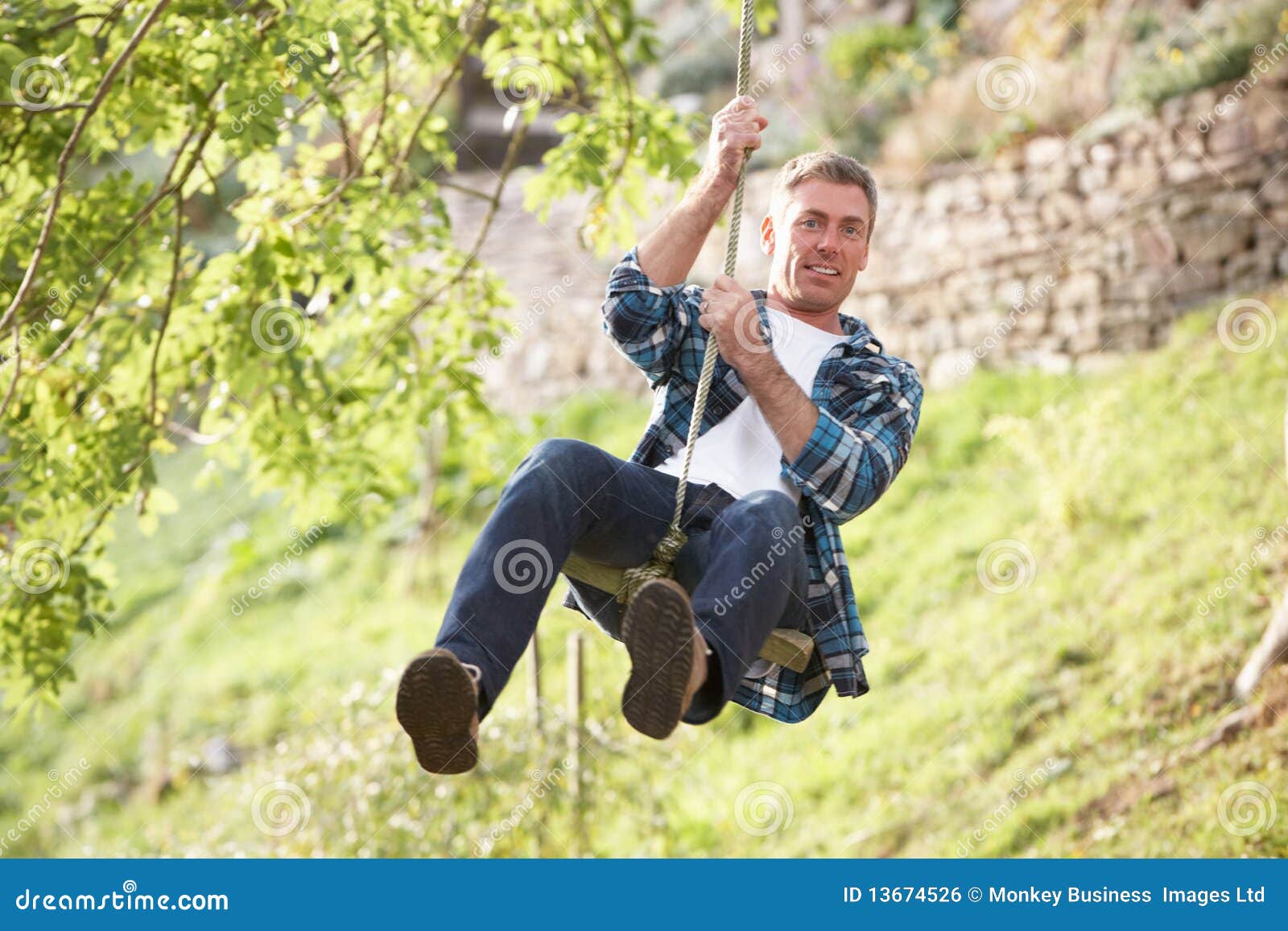 Man Having Fun On Woodland Swing Stock Photo Image of aged, outdoors