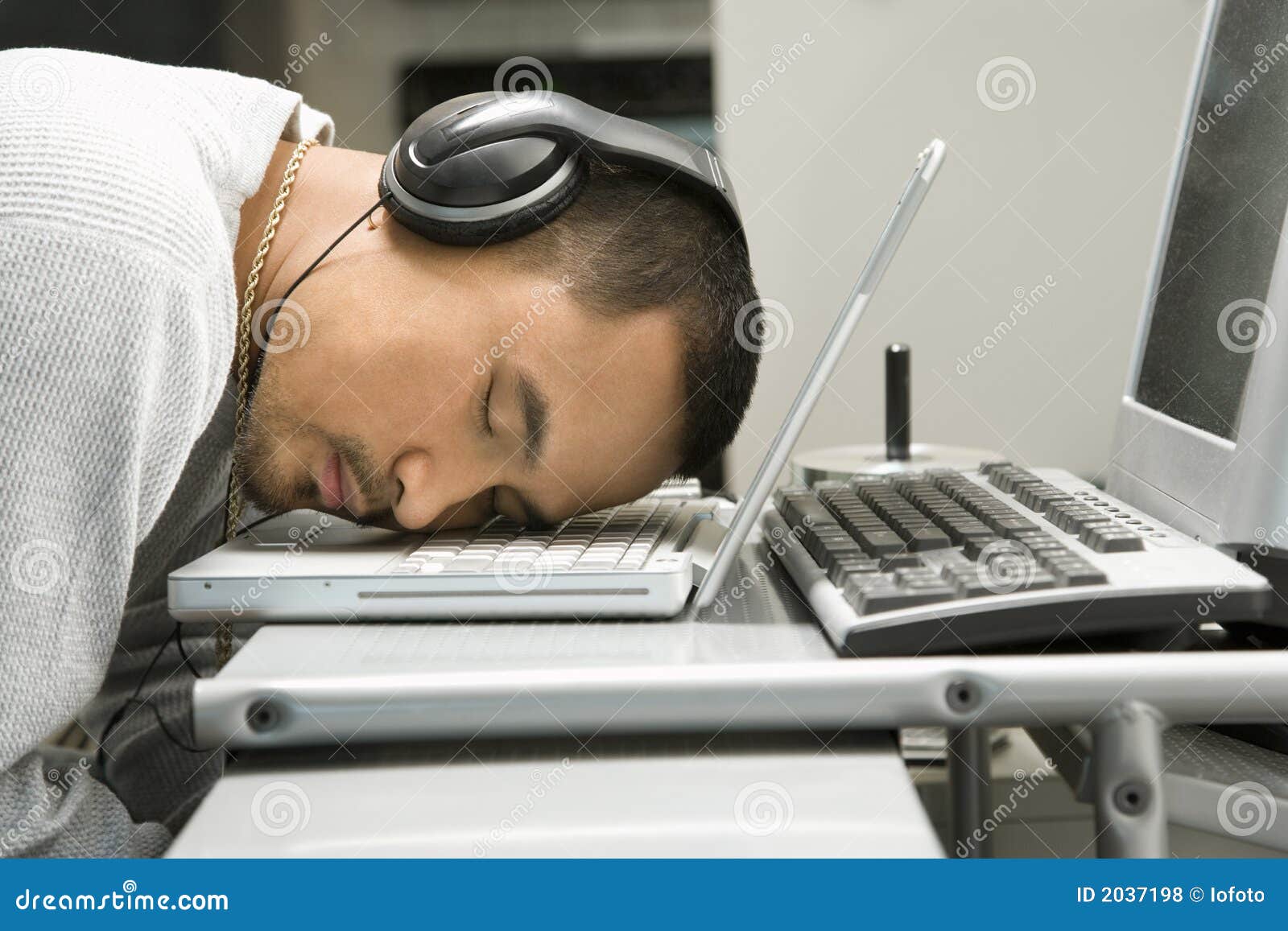 Man With Headphones Sleeping On Laptop. Stock Photo
