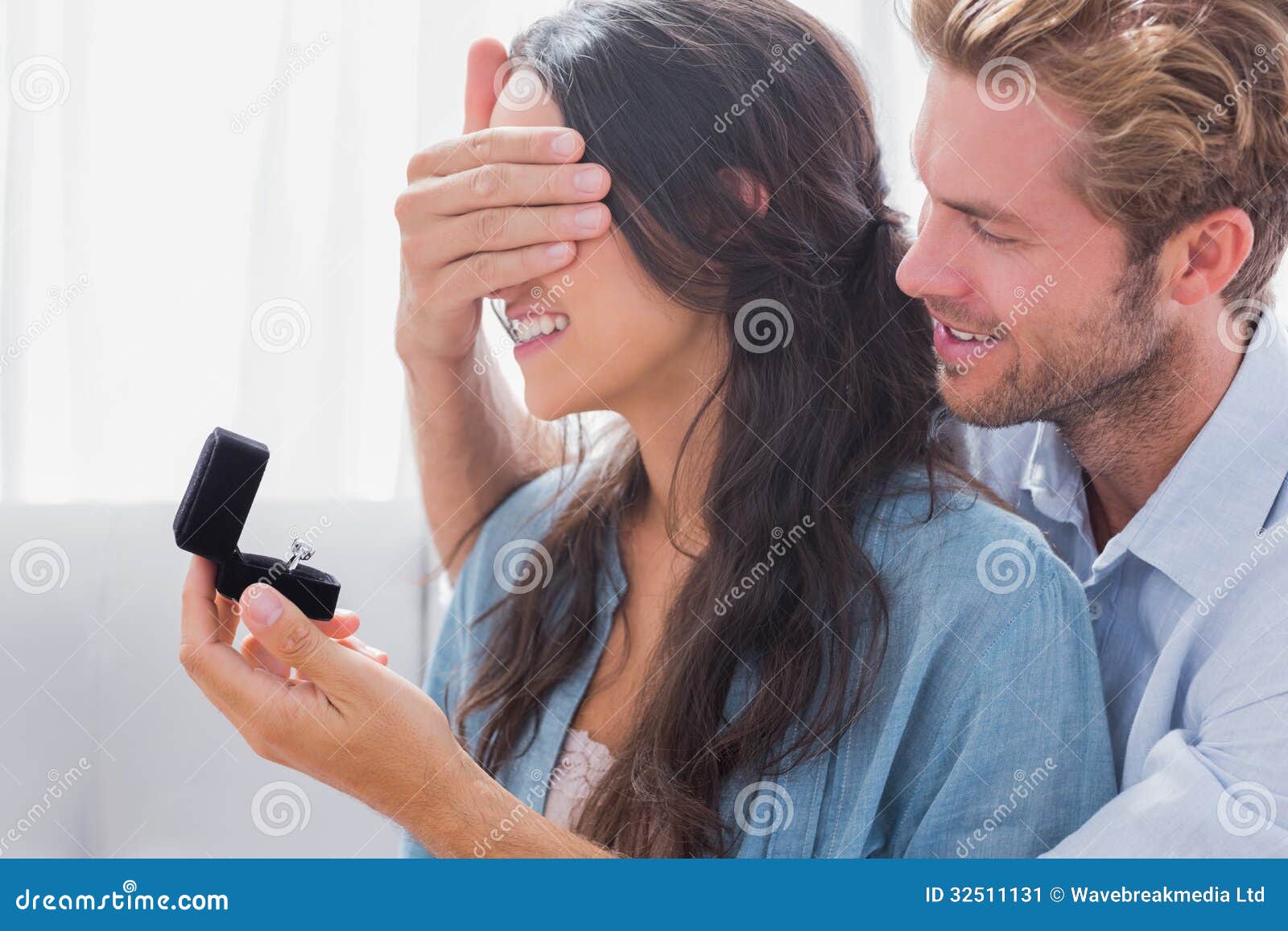 man hiding his wifes eyes to offer her an engagement ring