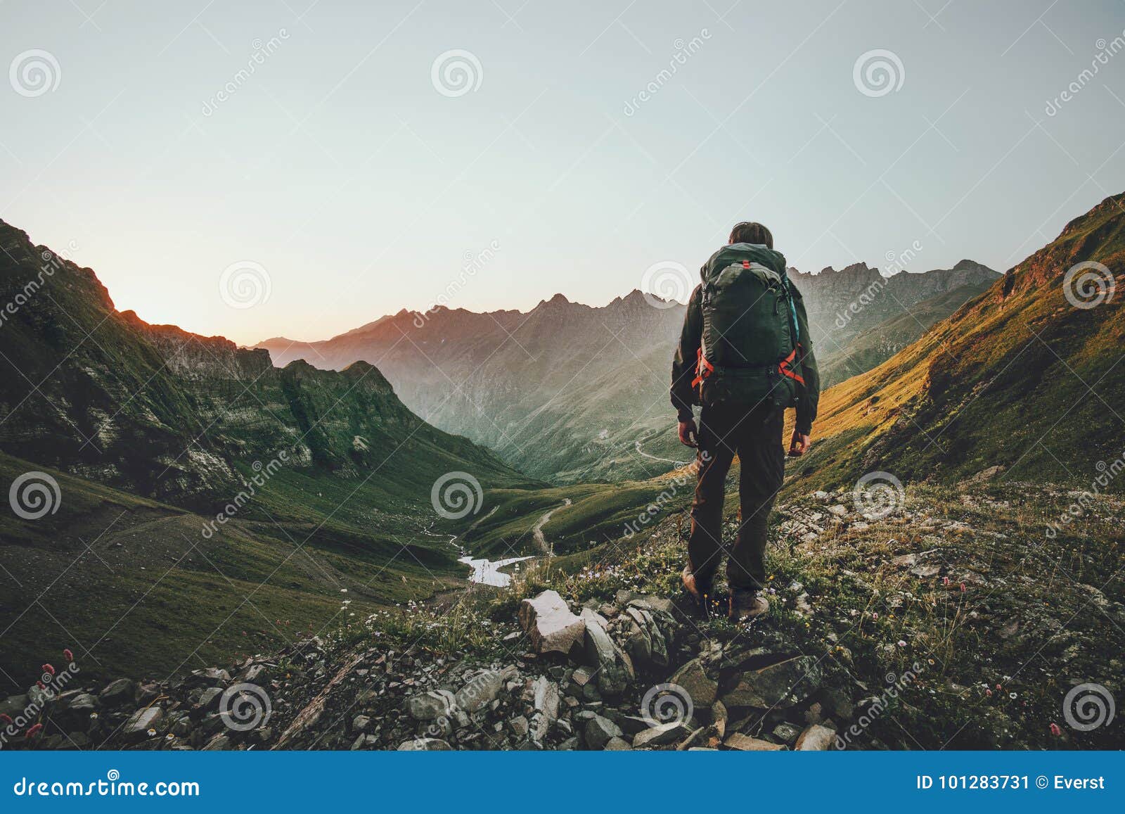 man hiking at sunset mountains with heavy backpack
