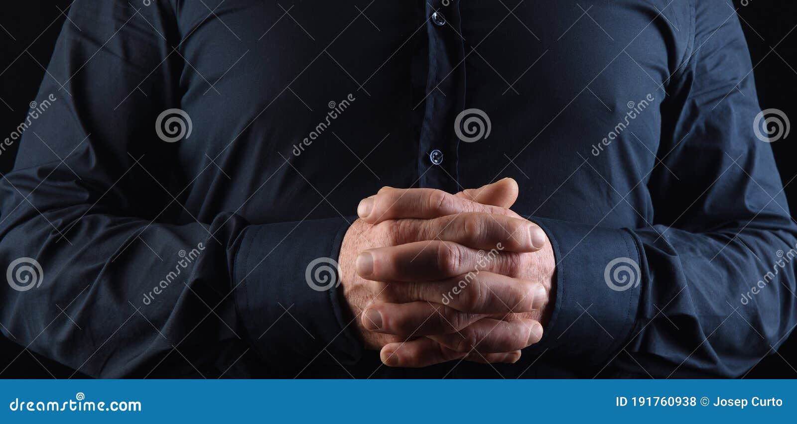 a man with his fingers interlocked on black