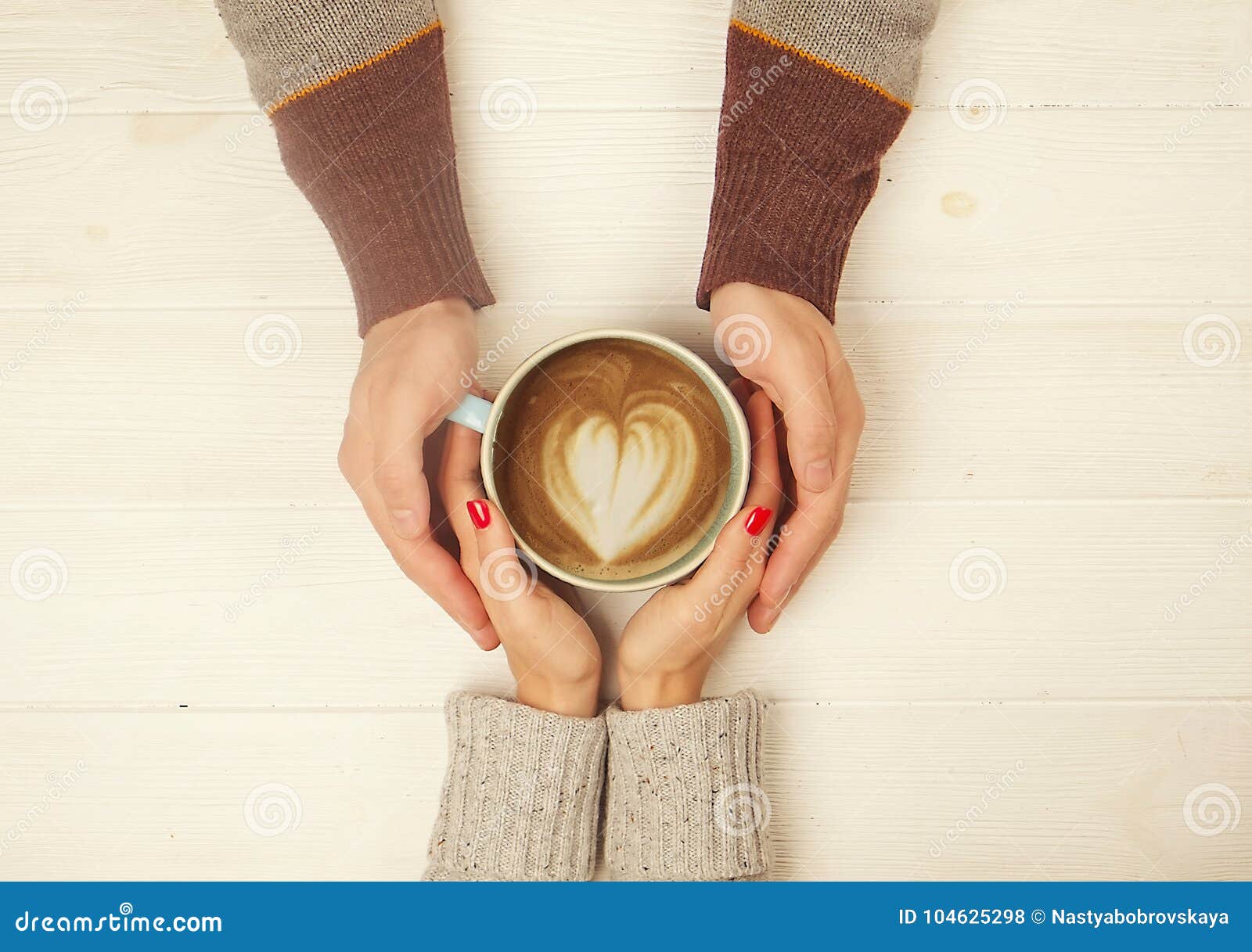 couple in love holding hands with cup of coffe top view image on white wooden background. man holds woman`s hand, love cosept.