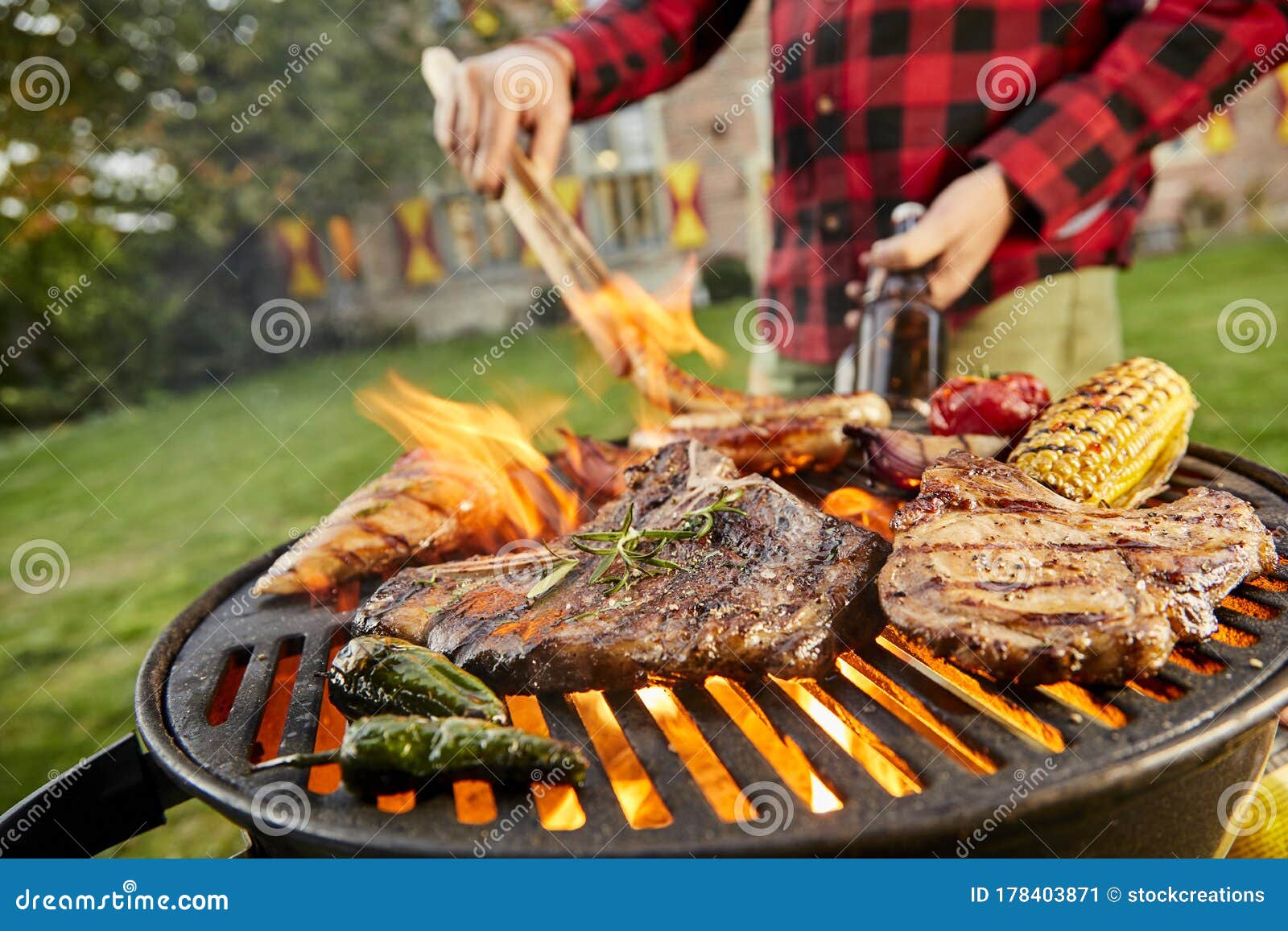 man holding a beer grilling meat on a bbq