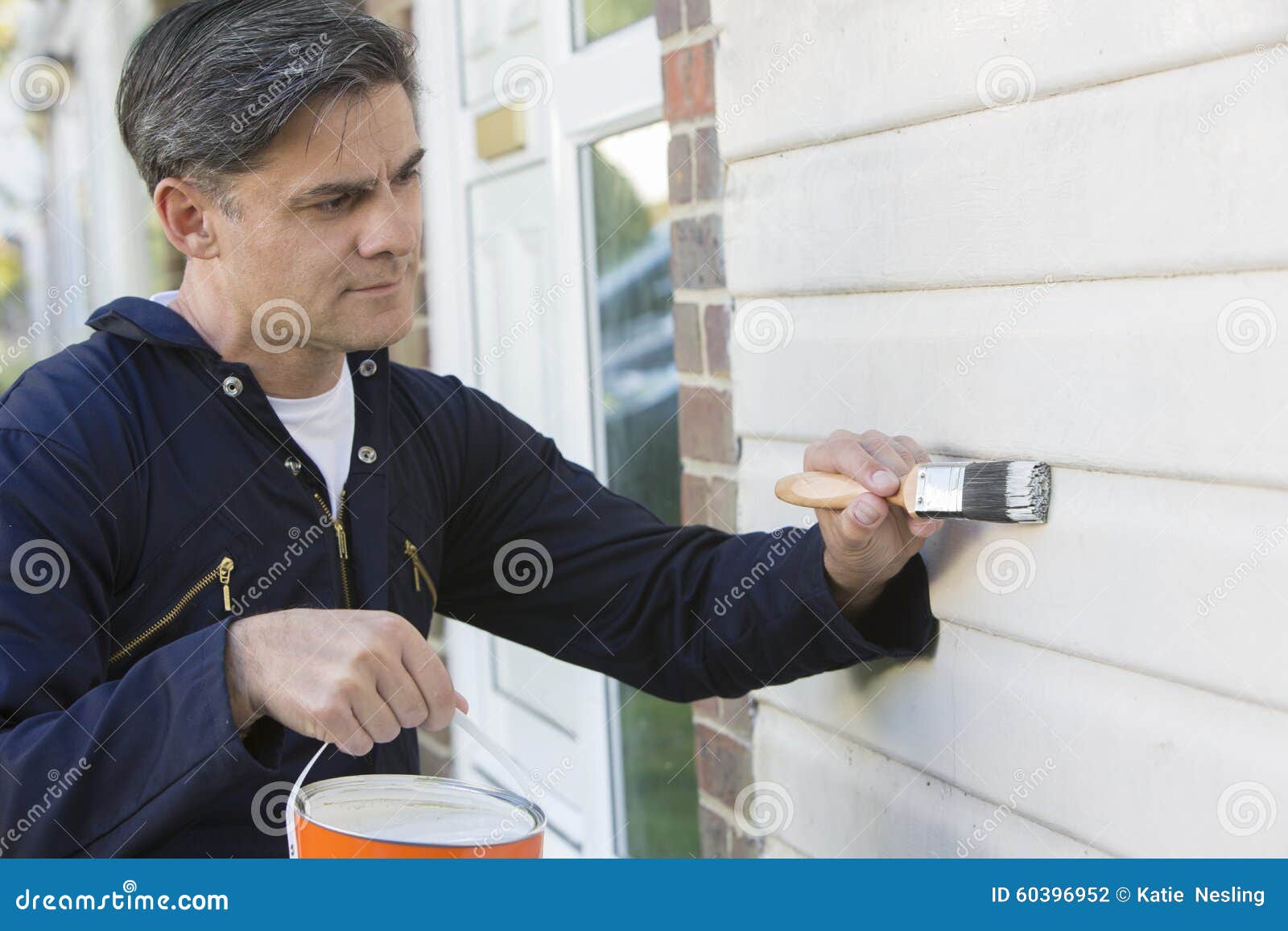man holding brush and tin painting outside of house