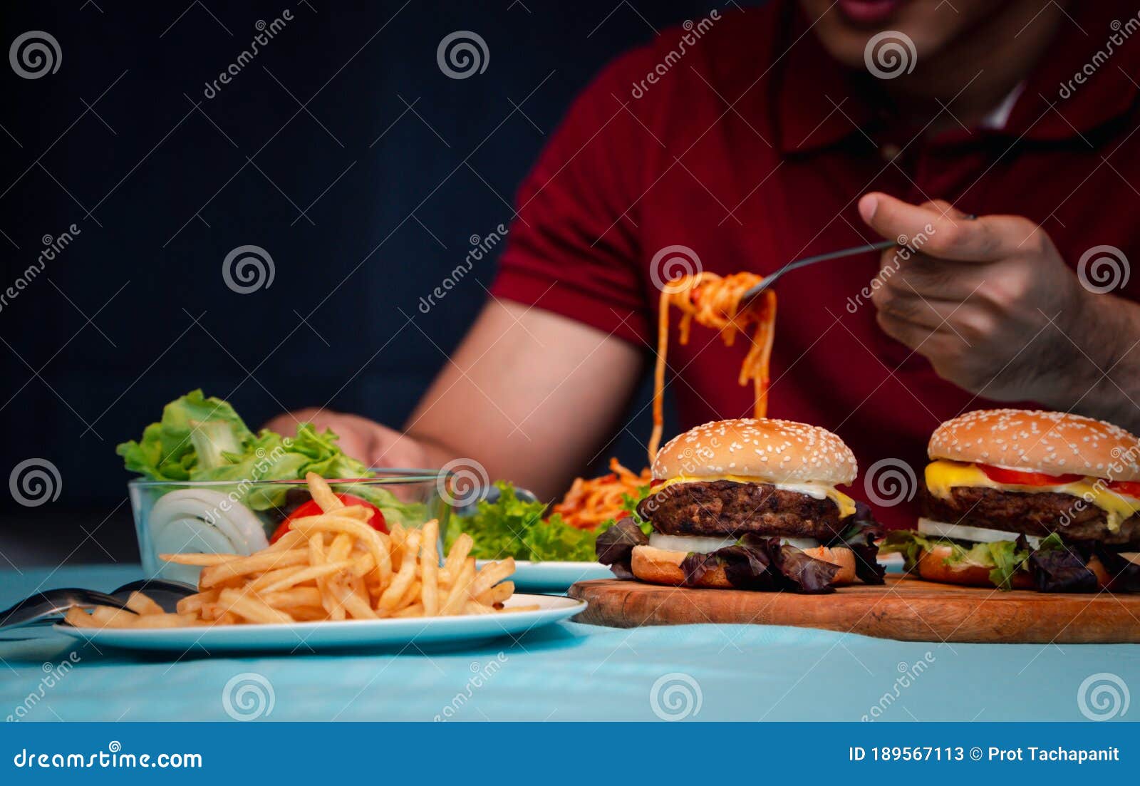 man holding hamburger on the wooden plate after delivery man delivers foods at home. concept of binge eating disorder bed and