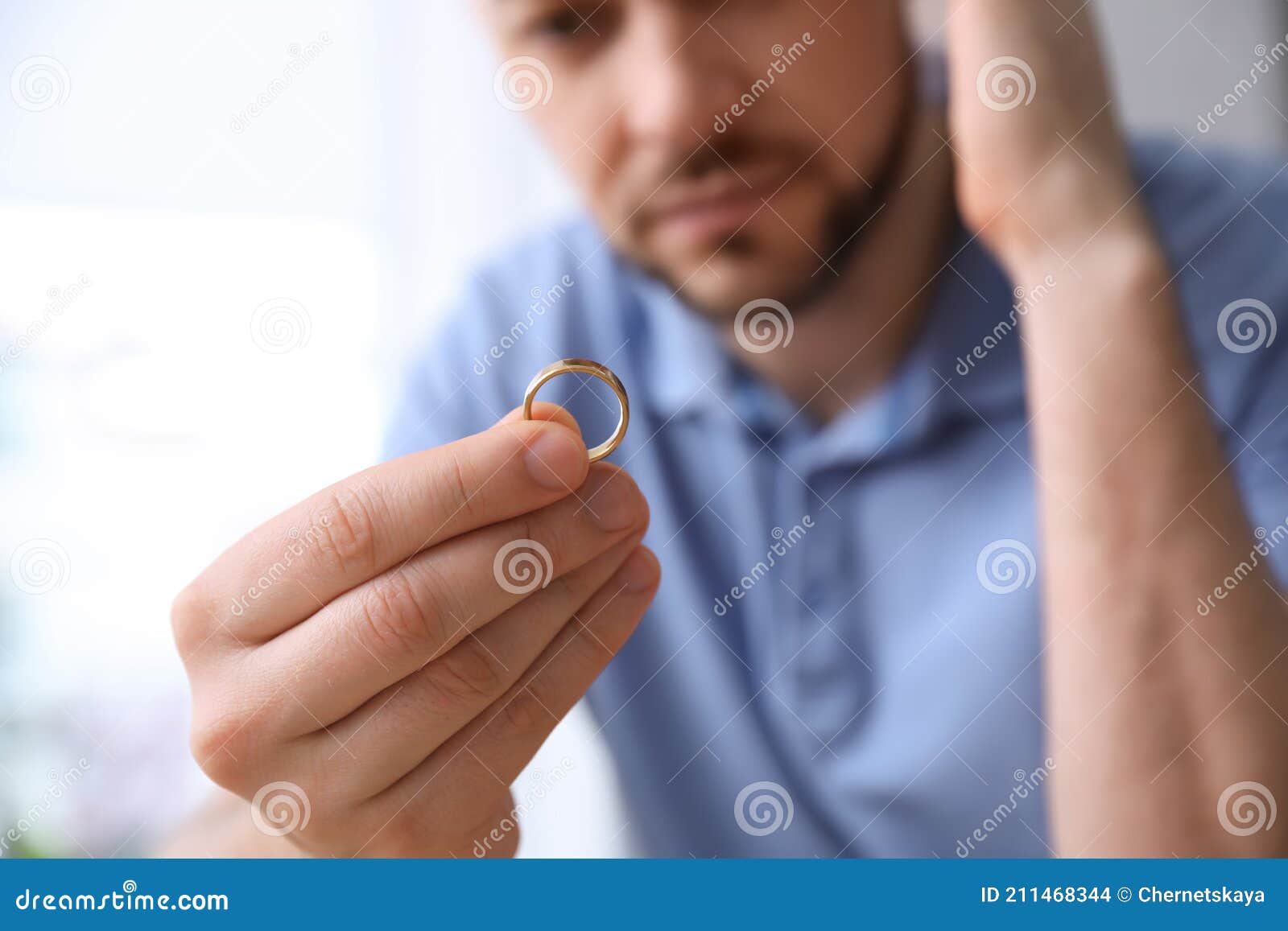 Man Holding Wedding Ring on Light Background, Closeup. Divorce Concept