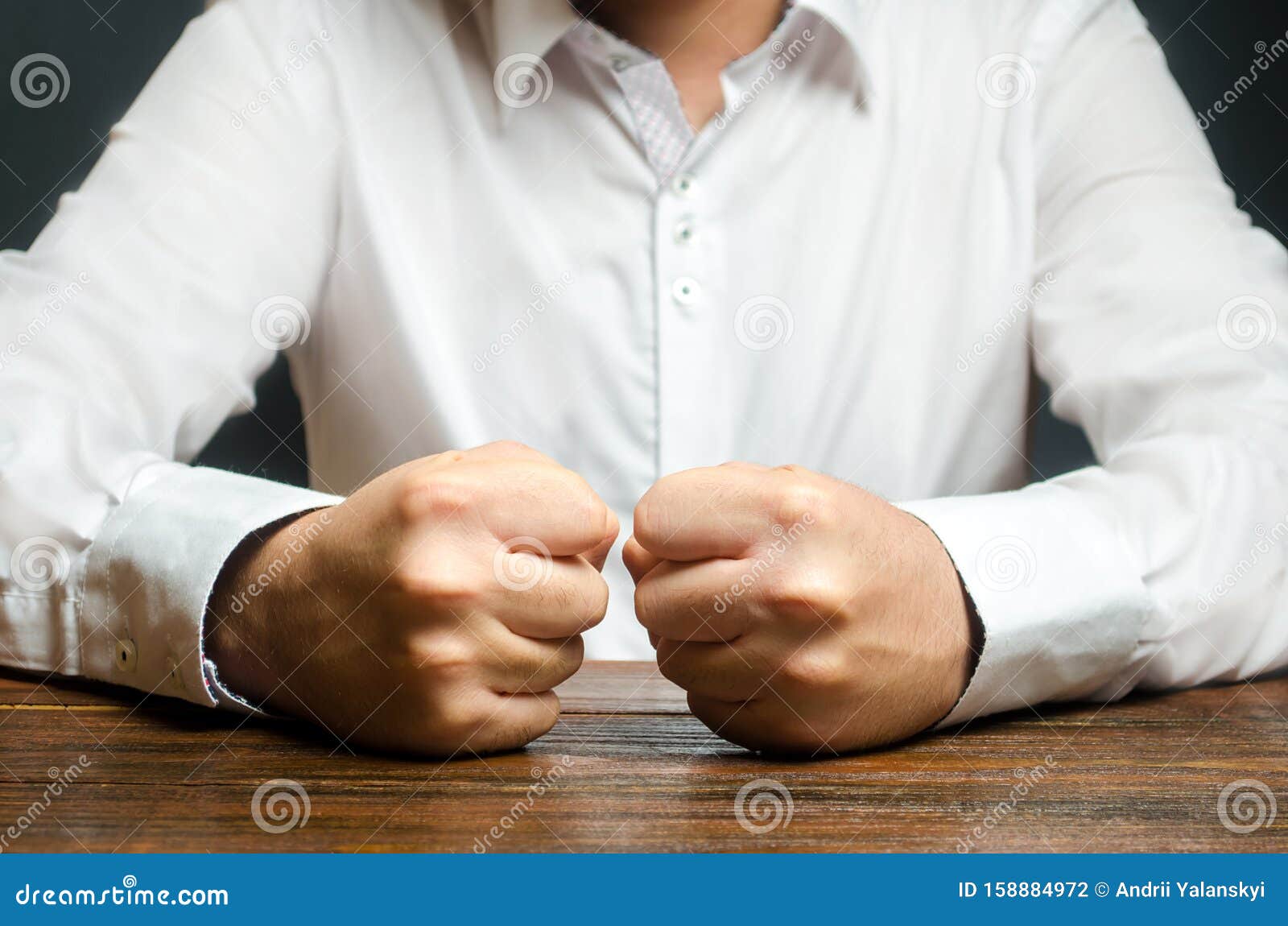 a man holds his closed fists on the table. the end of patience. it is impossible to bear it. an attack of anger, stress.