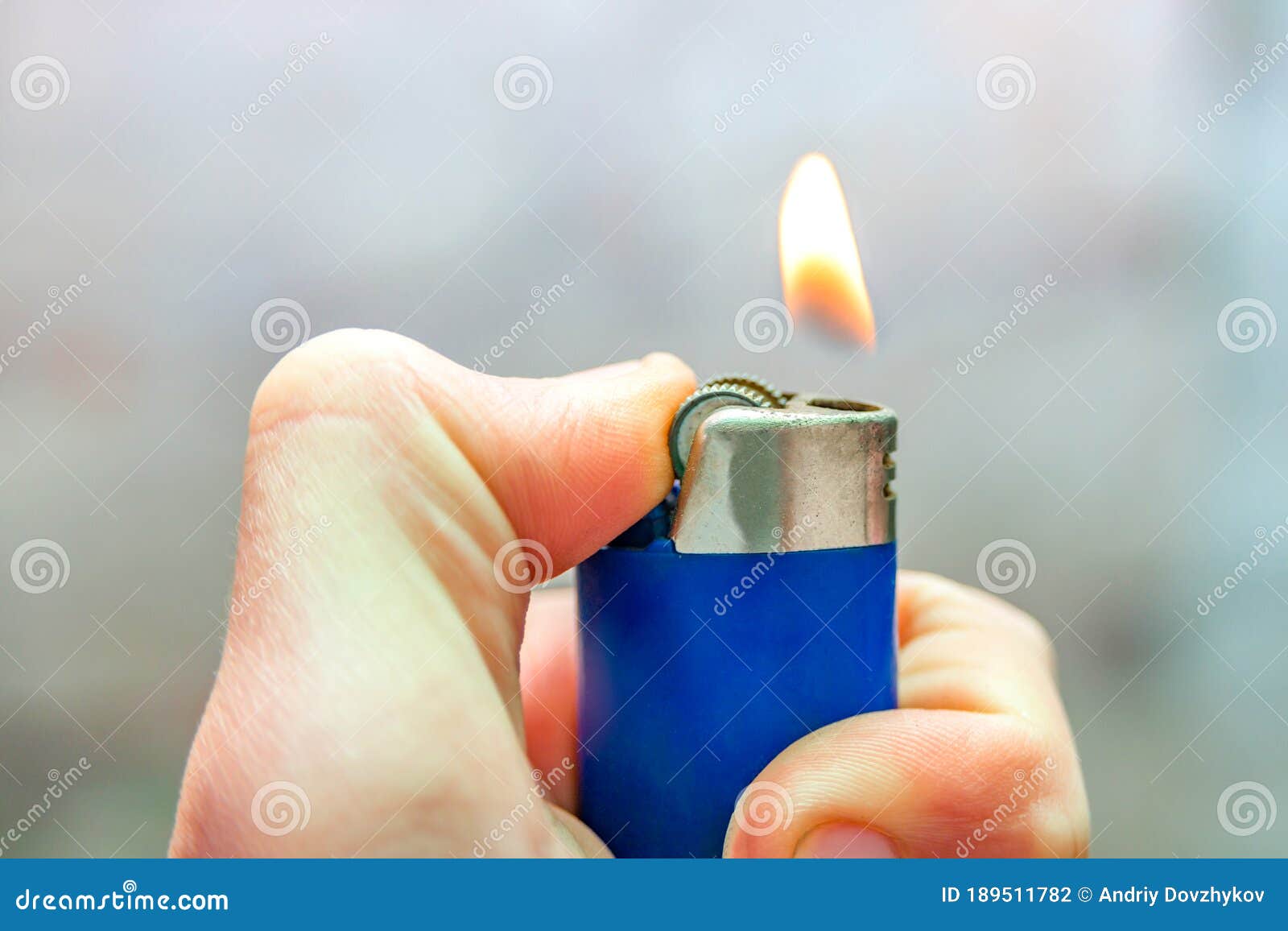 A Man Holds in His Hand a Lit Gas Lighter with a Flame, a Fire for