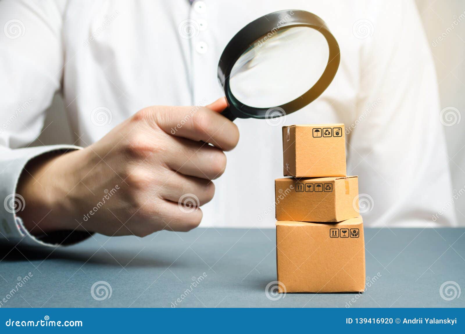 a man holds a magnifying glass above the boxes. examination of goods for the presence of contraband, prohibited goods, defects.