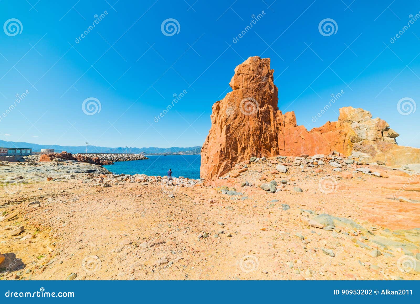 man by a huge rock in rocce rosse beach