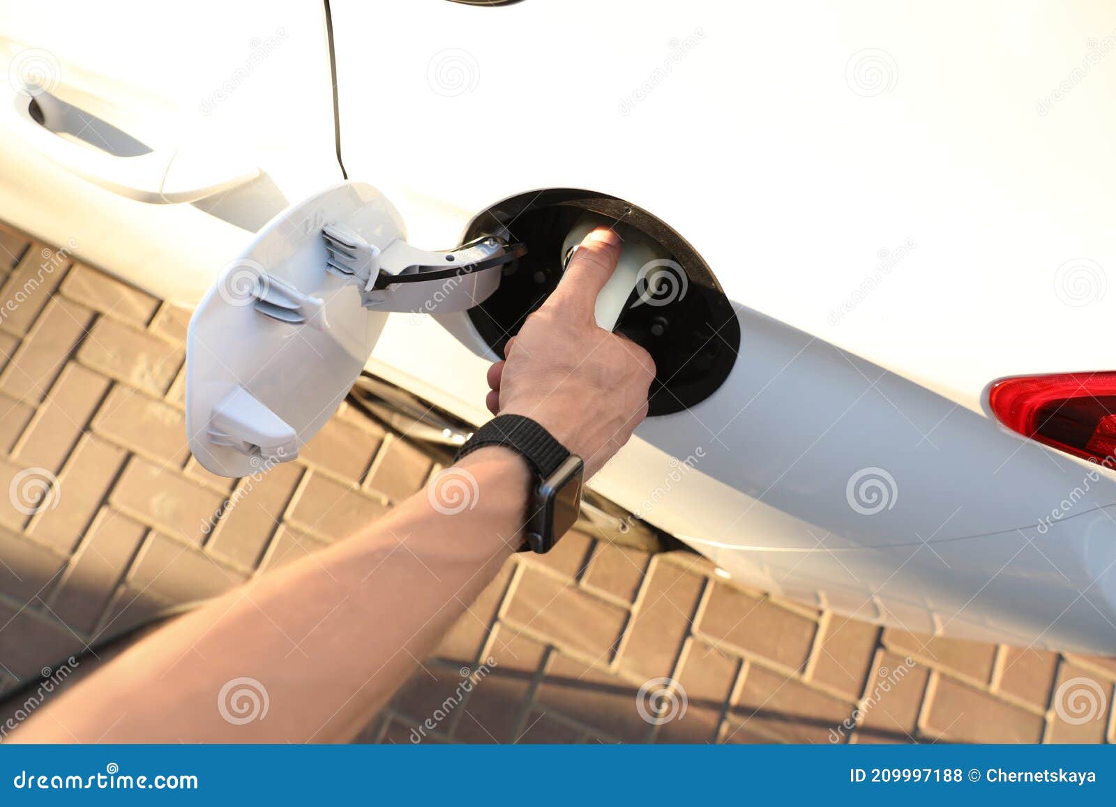 Man Inserting Plug into Electric Car Socket at Charging Station, Above