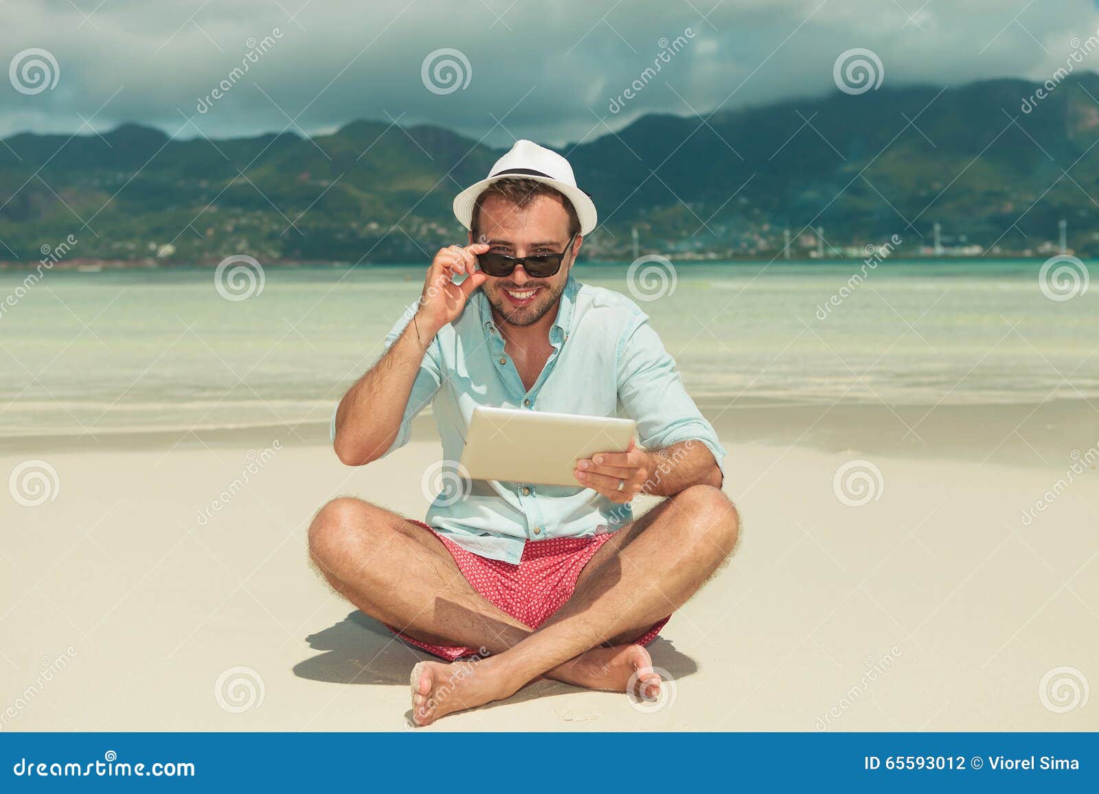 Man with Ipad on the Beach Smiling and Fixing His Sunglasses Stock ...