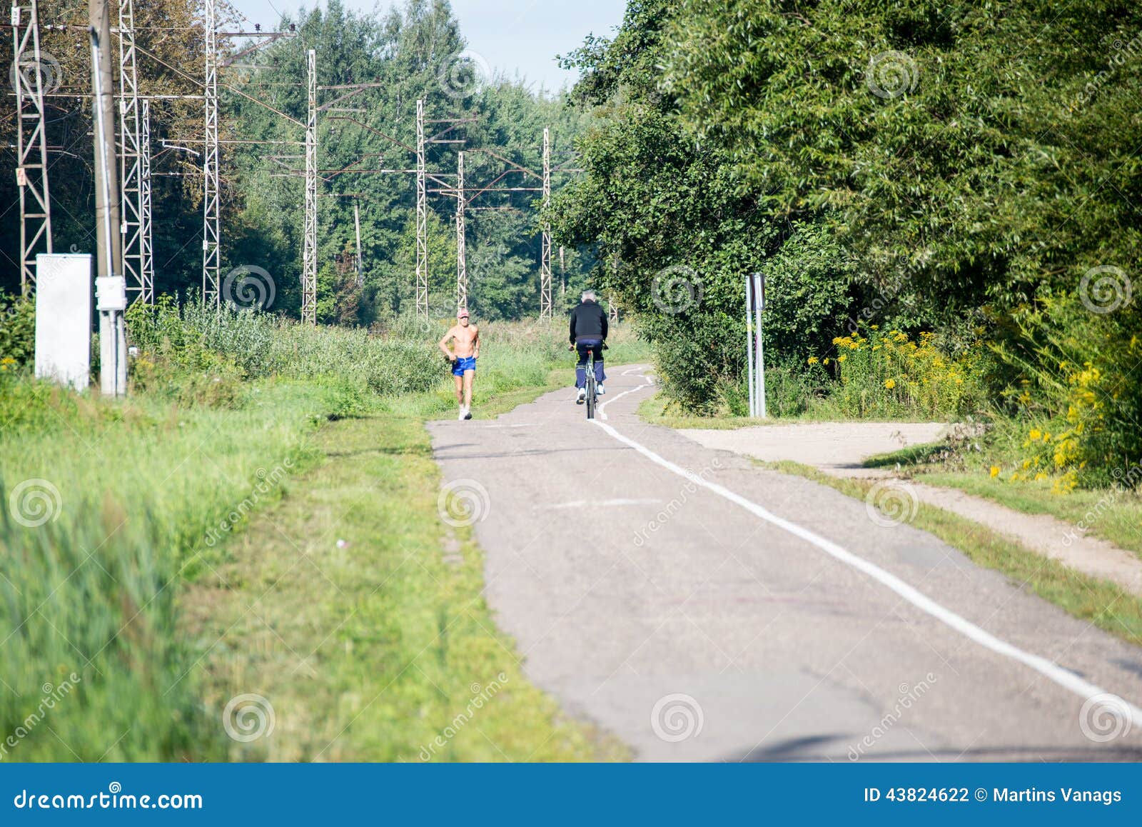 Man Jogging and Man Cycling on the Road Editorial Photography Image