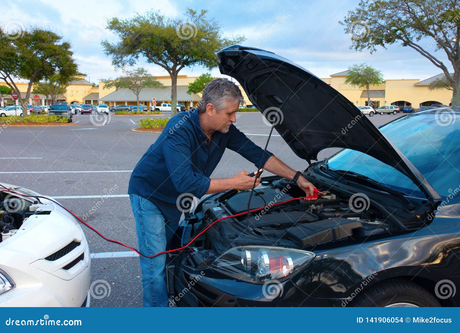 man jump starting a car with jumper cables
