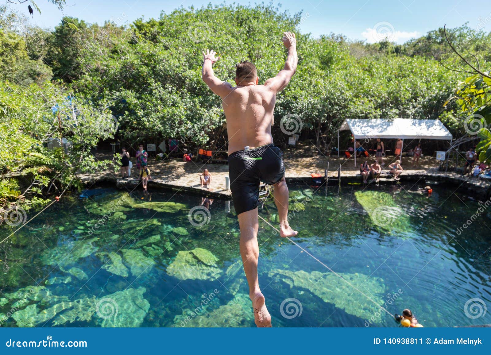 man jumps off a cliff into the cristalino cenote in mexico.