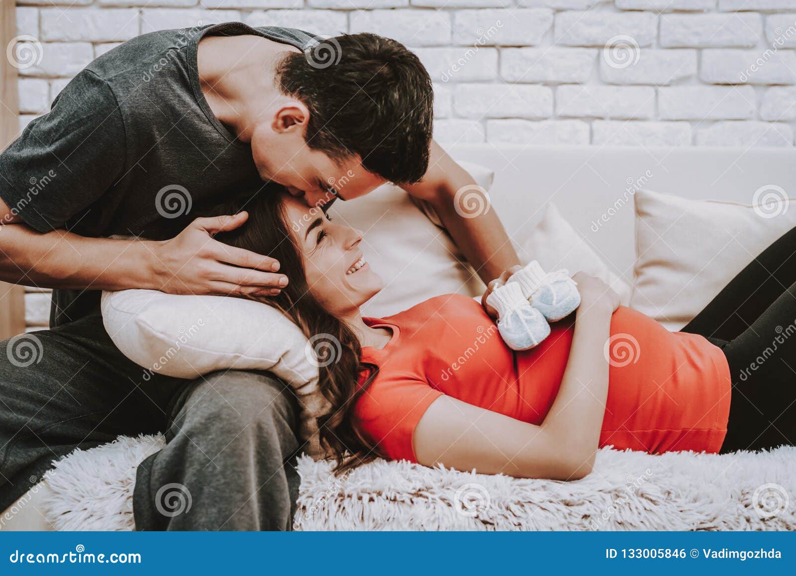 Husband and Pregnant Wife Relaxing on Couch Stock Photo picture
