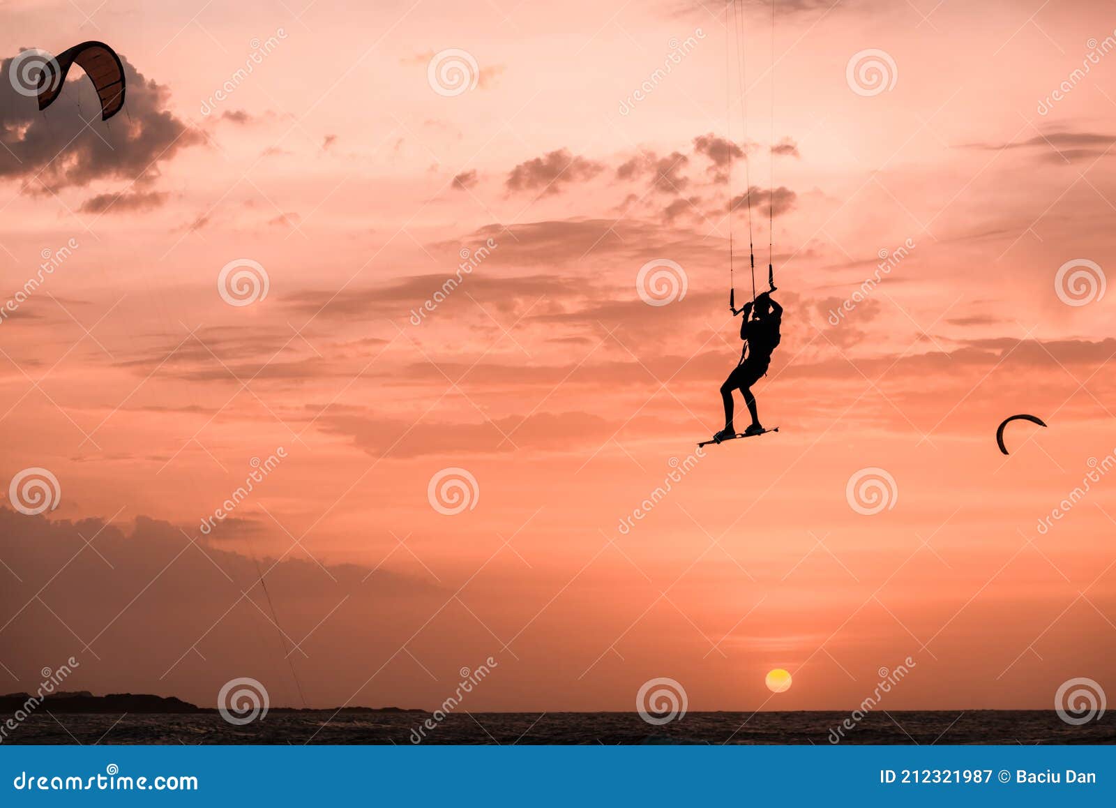 man kitesurfer jumping at sunset, silhouette of kitesurf jump on orange background at golden hour