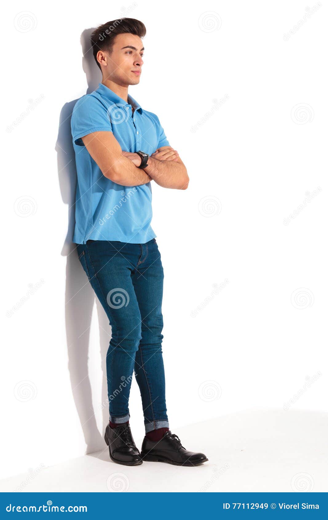 man leaning against studio wall with hands crossed