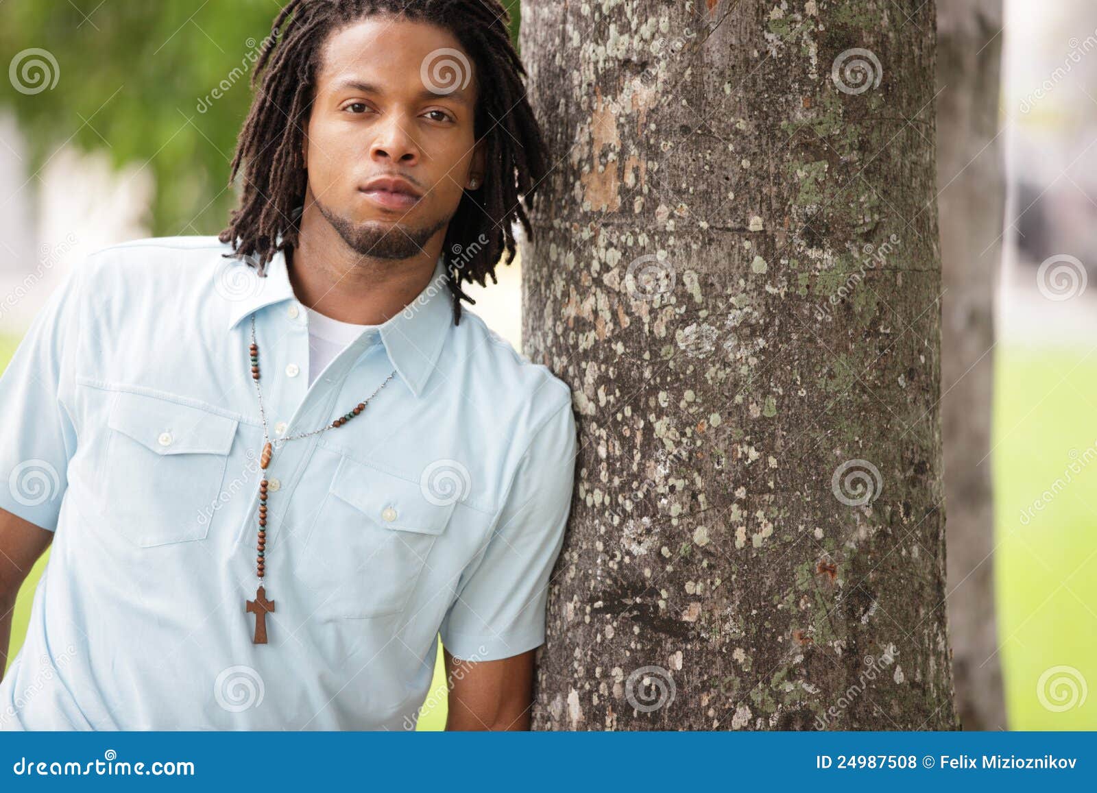 Man leaning on a tree. Image of a young black male leaning on a tree