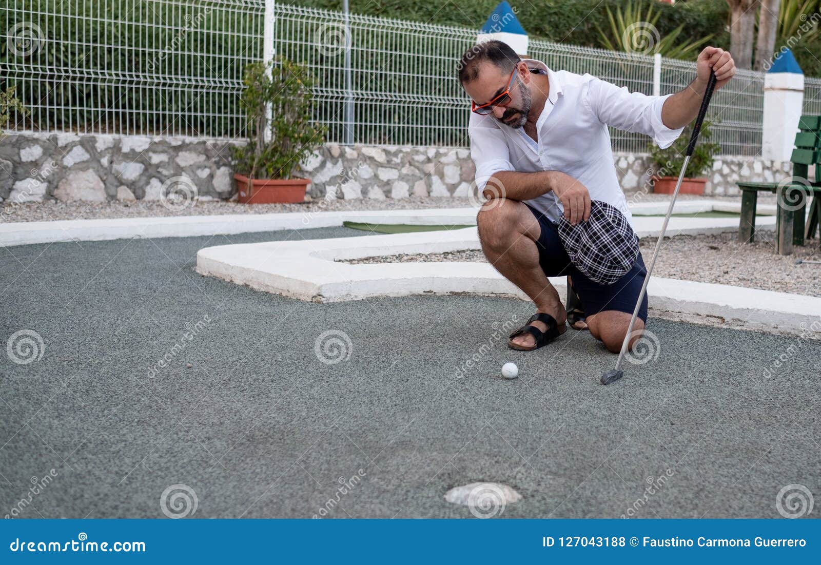 Man Looking at Golf Ball with Stick in Hand before Throwing Stock Photo